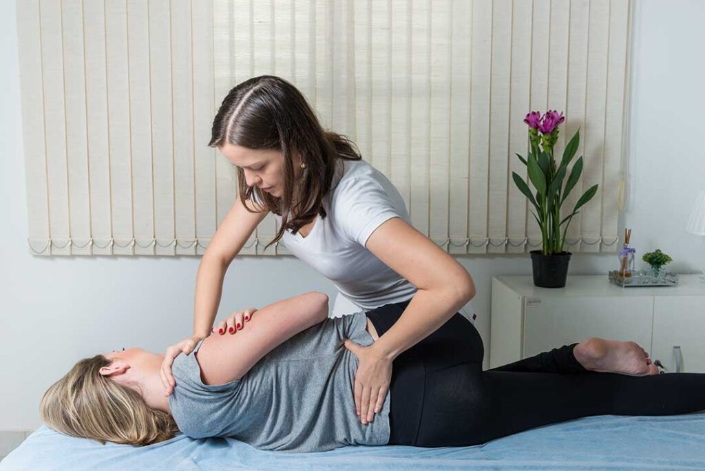 Middle-aged person holding their lower back with a look of concern in a typical home setting.